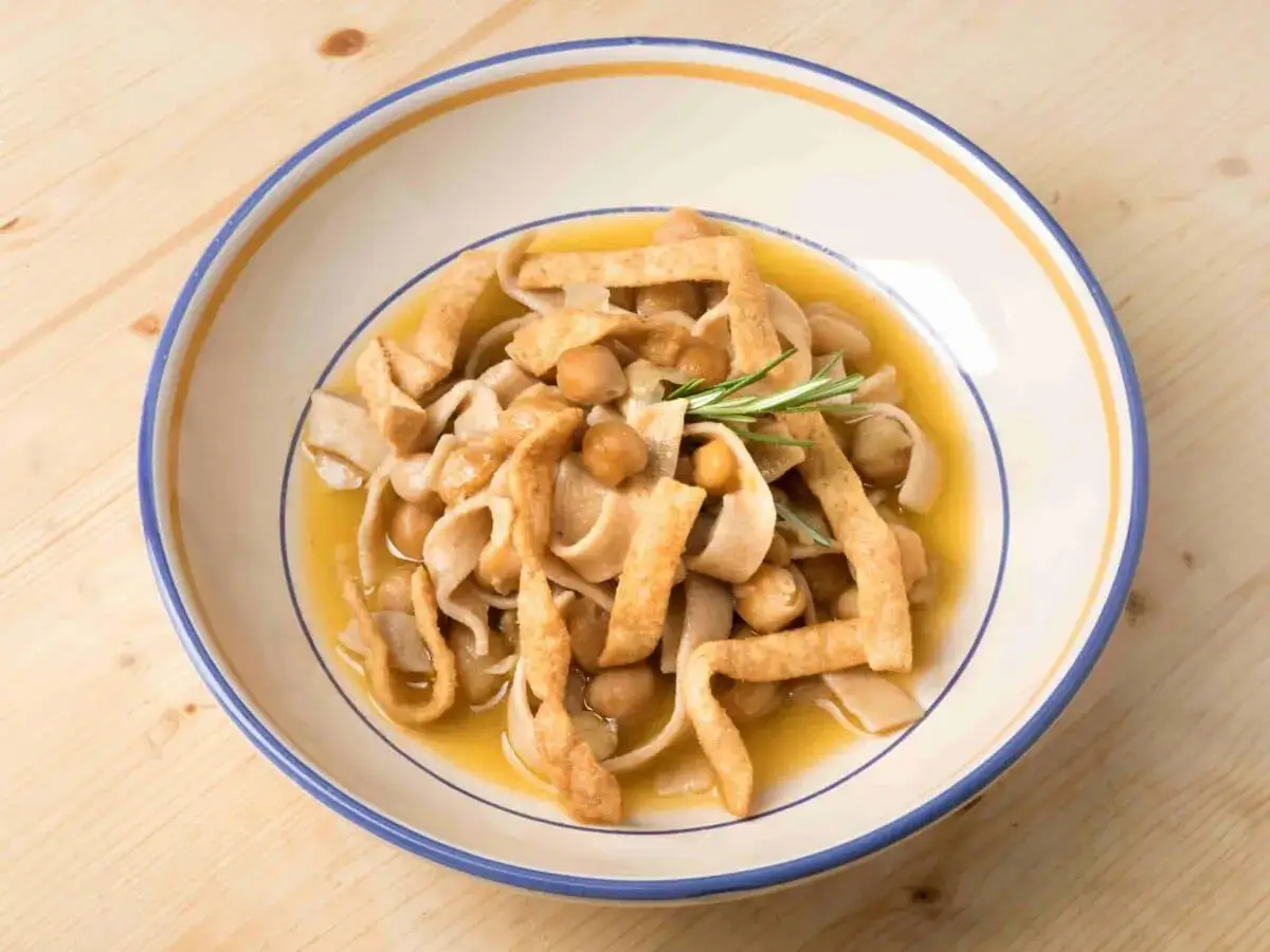 Piatto di ciceri e tria, pasta fresca con ceci e croccanti straccetti fritti, guarnito con rosmarino.
