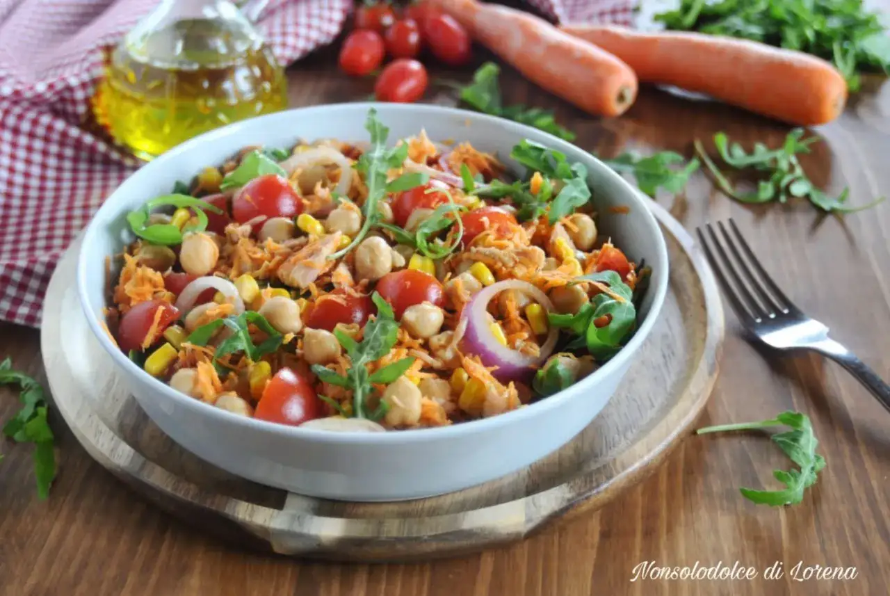Insalata di ceci e tonno con pomodorini, mais, carote grattugiate e rucola. Fresca e colorata, perfetta per un pasto leggero.