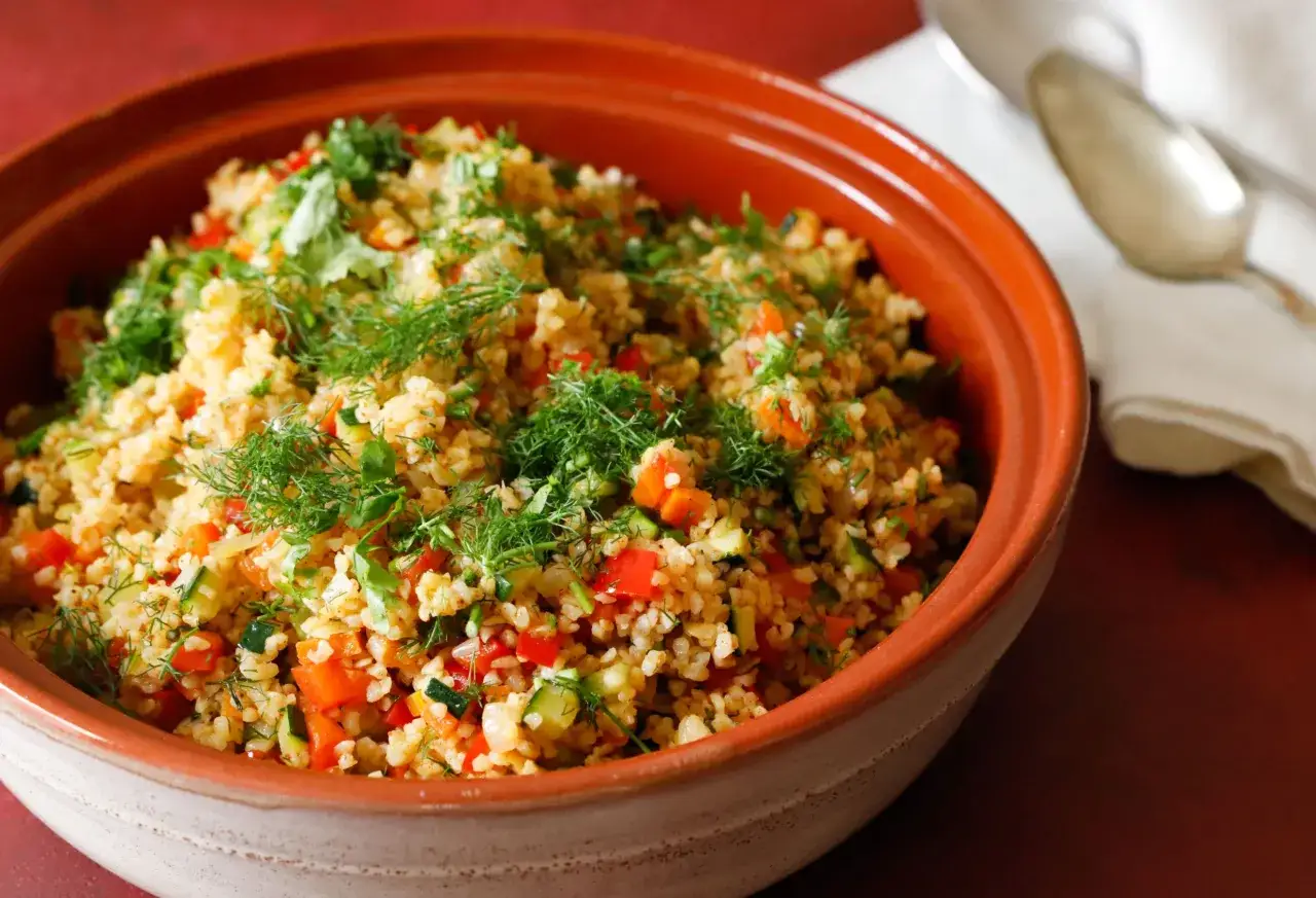 Un invitante tabulè di verdure, ricco di pomodori, zucchine e erbe fresche, pronto per essere gustato.