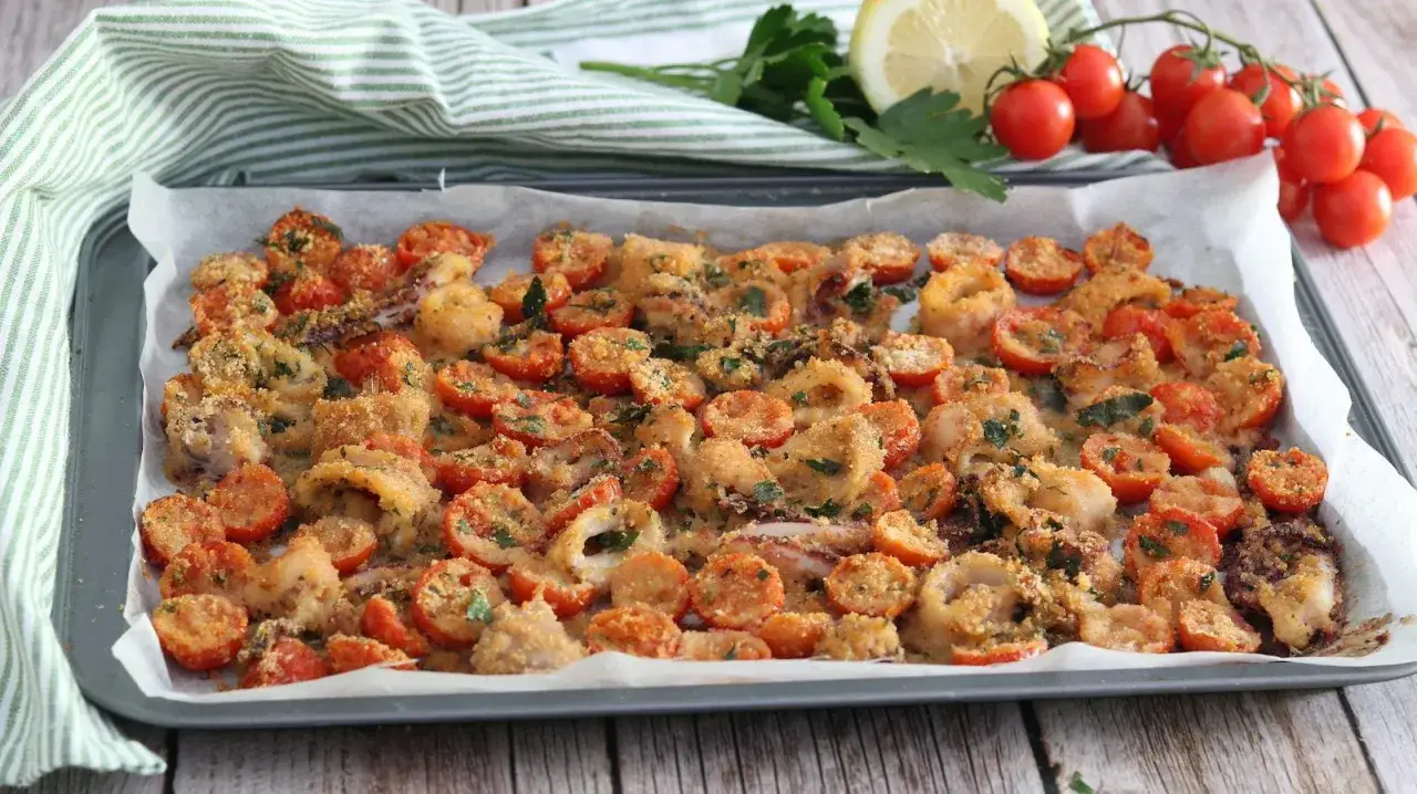 Anelli di totano al forno con pomodorini e pangrattato, un piatto saporito e leggero, pronto per essere gustato.