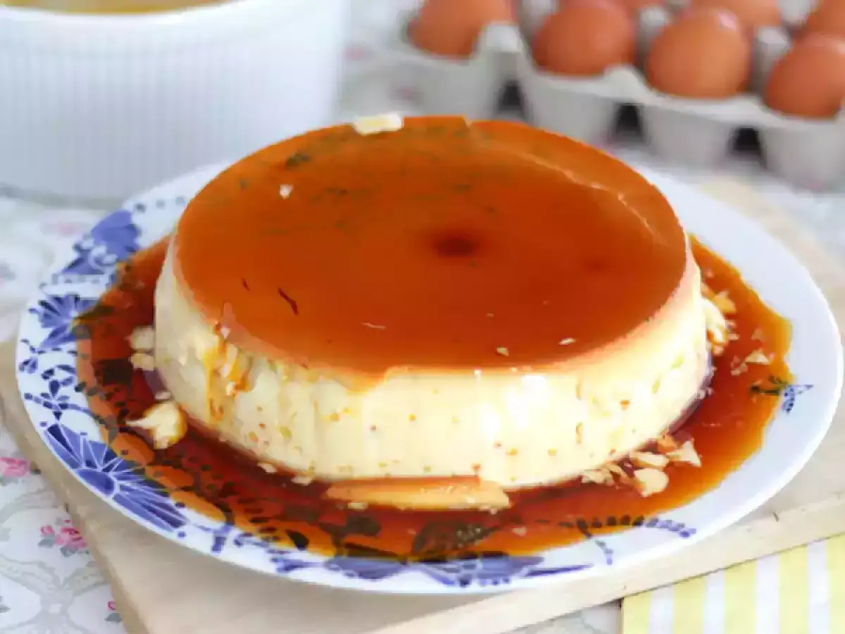 Delizioso latte alla portoghese su un piatto decorato, con caramello dorato che cola. Sullo sfondo, uova fresche pronte per la preparazione.