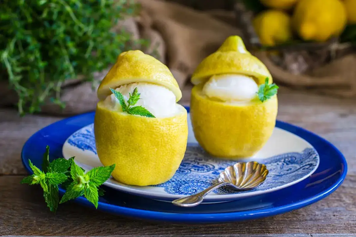 Due limoni scavati servono da coppette per un rinfrescante gelato al limone, guarnito con menta fresca.