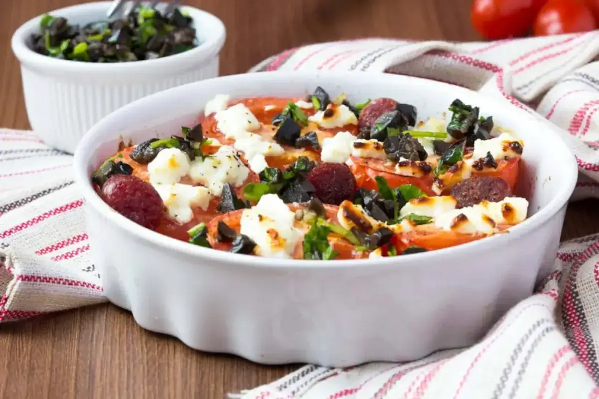 Feta al forno con pomodori, olive nere e erbe aromatiche, un piatto invitante e saporito.