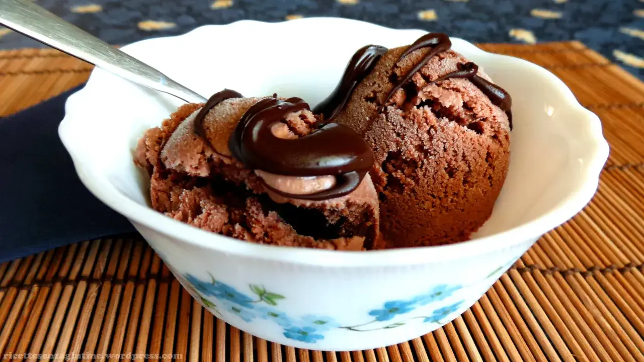 Gelato al cioccolato fatto in casa, perfetto per chi vuole imparare come fare il gelato senza gelatiera. Servito in una ciotola con salsa al cioccolato.