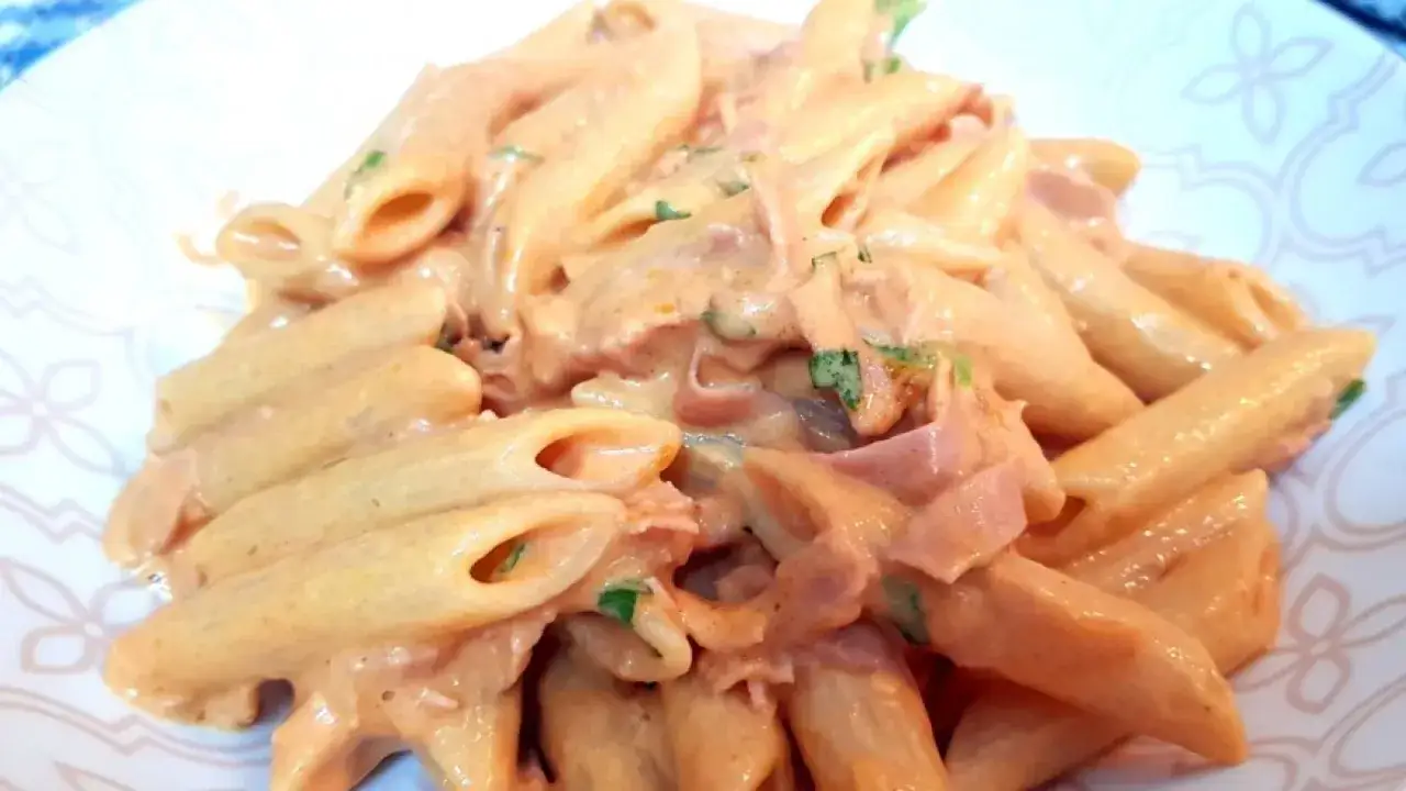 Penne al baffo cremose con prosciutto e prezzemolo, un piatto che fa venire l'acquolina in bocca.