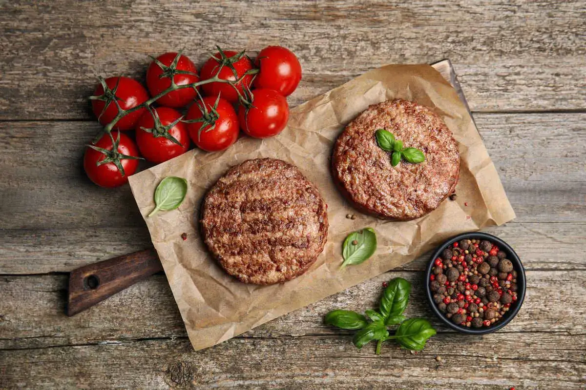 Due hamburger in friggitrice ad aria pronti per essere gustati, con pomodorini freschi e basilico.