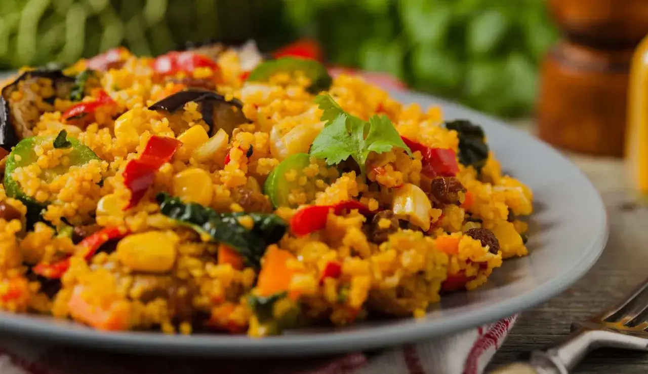 Un piatto colorato con cous cous, verdure miste e uvetta. Una ricetta cous cous originale che invita a scoprire sapori esotici.
