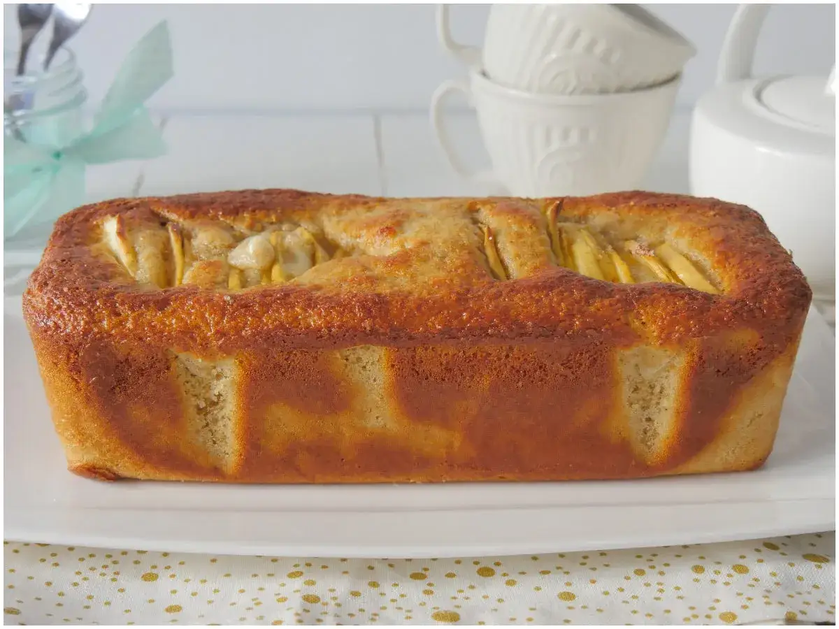 Un delizioso plumcake alle mele dorato, con pezzi di mela visibili in superficie, pronto per essere gustato.