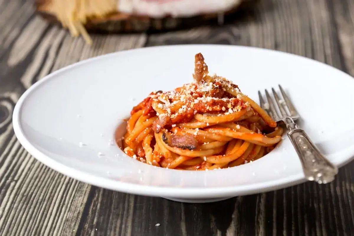 Un piatto di bucatini all'amatriciana ricetta originale di Amatrice, conditi con guanciale croccante e pomodoro.