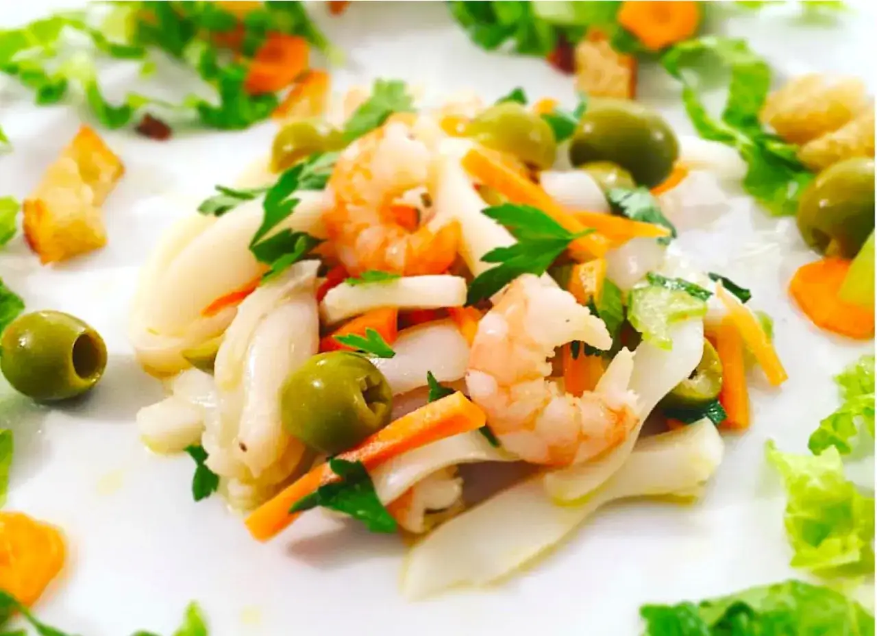 Deliziosa insalata di mare con verdure, gamberetti, calamari, olive e carote, guarnita con prezzemolo fresco.