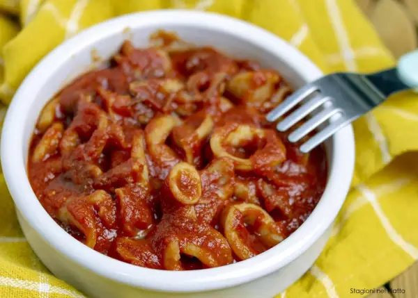 Calamari in umido, un piatto saporito e profumato, servito in una ciotola bianca su un tovagliolo giallo.